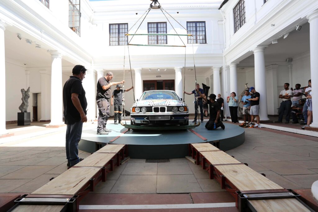 A Retrospective Unveiling: A Life of Artistic Brilliance 9 Esther Mahlangu. Car being attached to crane.