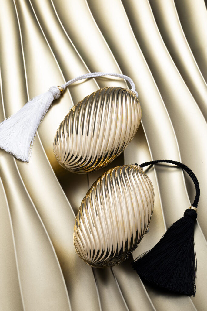 Bvlgari Melone Clutch Returns From the Archive 13 Bvlgari Melone clutch in pleated gold finish aluminium with a white mother of pearl cabochon closure and silk tassel