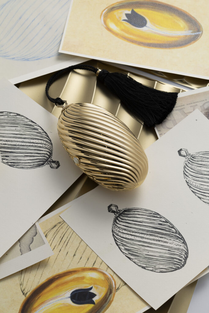 Bvlgari Melone Clutch Returns From the Archive 16 Bvlgari Melone clutch in pleated gold finish aluminium with a white mother of pearl cabochon closure and silk tassel