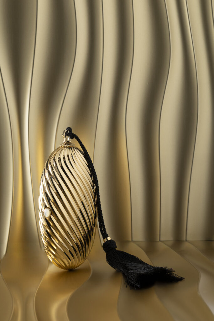 Bvlgari Melone Clutch Returns From the Archive 3 Bvlgari Melone clutch in pleated gold finish aluminium with a white mother of pearl cabochon closure and silk tassel
