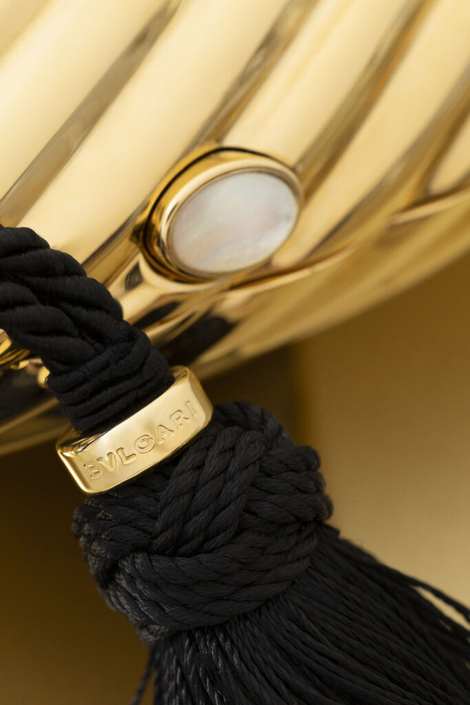 Bvlgari Melone Clutch Returns From the Archive 2 Bvlgari Melone clutch in pleated gold finish aluminium with a white mother of pearl cabochon closure and silk tassel