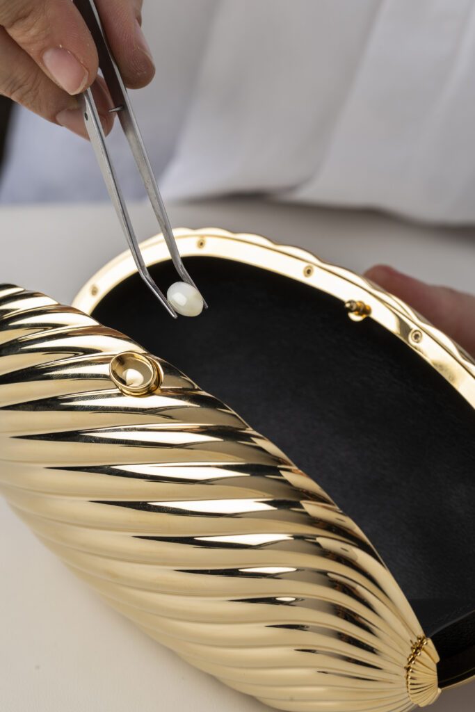 Bvlgari Melone Clutch Returns From the Archive 14 Bvlgari Melone clutch in pleated gold finish aluminium with a white mother of pearl cabochon closure and silk tassel