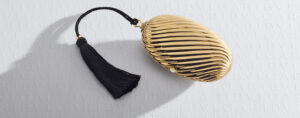 Bvlgari Melone clutch in pleated gold finish aluminium with a white mother of pearl cabochon closure and silk tassel