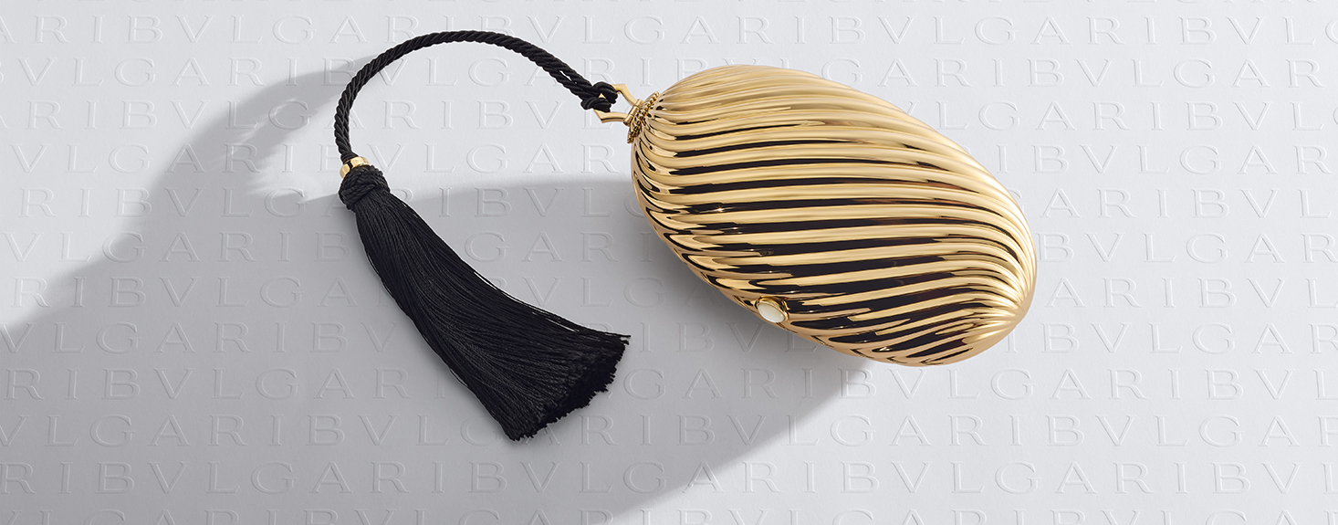 Bvlgari Melone clutch in pleated gold finish aluminium with a white mother of pearl cabochon closure and silk tassel